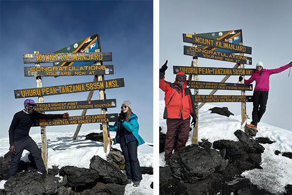 Kilimanjaro porter standing with a trekker at Uhuru Peak summit sign after a successful climb