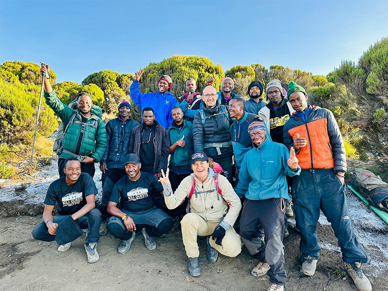 Kilimanjaro trekkers and porters smiling together at the end of a successful hike