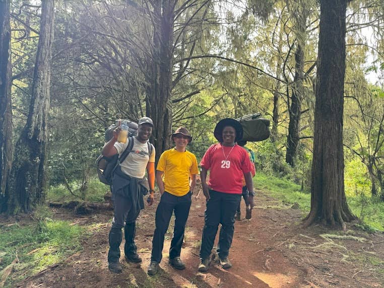 Trekkers and porters hiking through the forest into the moorland zone on the Lemosho Route, Mount Kilimanjaro | Kili Quests