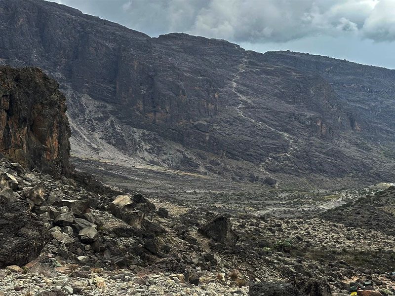 Trekker walking at high altitude toward Kilimanjaro’s summit | Kili Quests