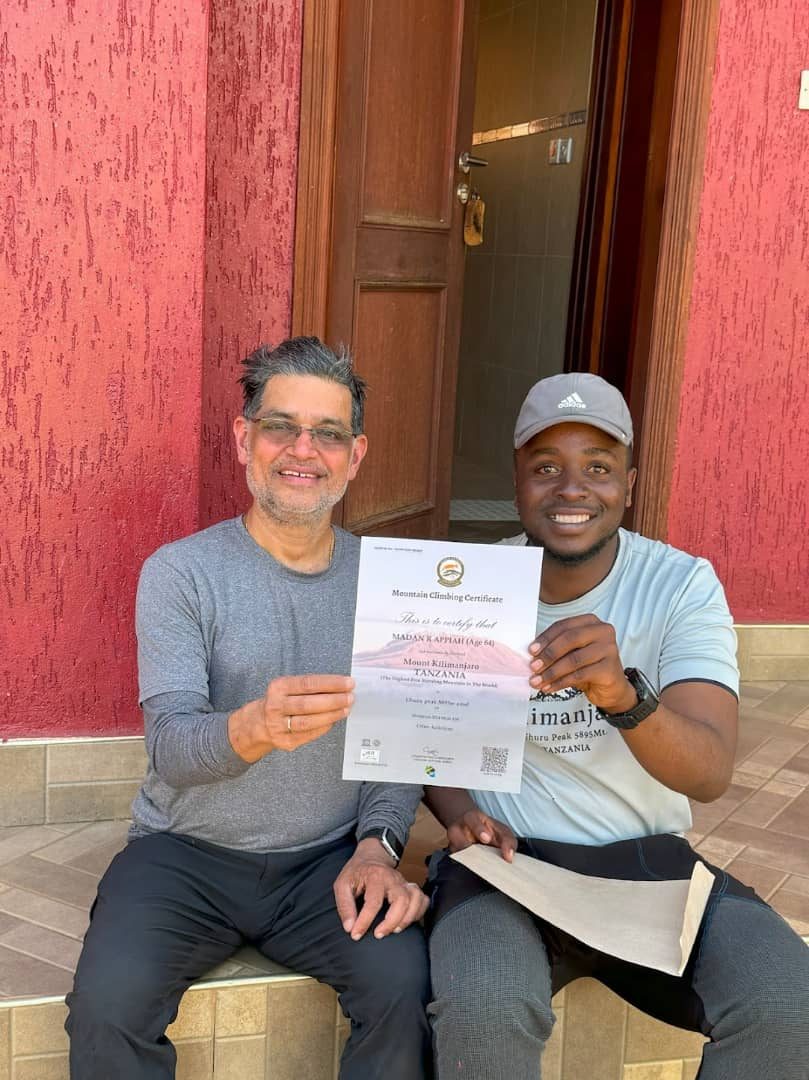 A climber proudly holding a Mount Kilimanjaro summit certificate with their Kili Quests guide after completing the trek to Uhuru Peak | Kili Quests
