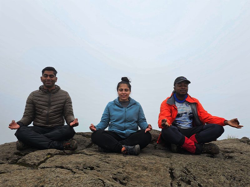 Trekkers meditating on a rock during a peaceful break on the Machame Route, Mount Kilimanjaro | Kili Quests