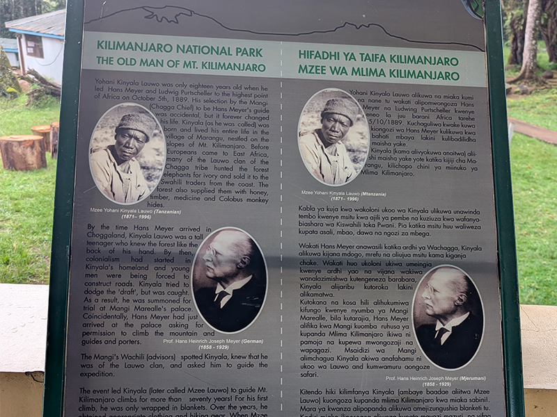 Interpretive sign at Kilimanjaro National Park showing historical profiles of Yohani Kinyala Lauwo, the first local guide of Mount Kilimanjaro, and Hans Meyer, the first recorded European to summit Kilimanjaro in 1889.