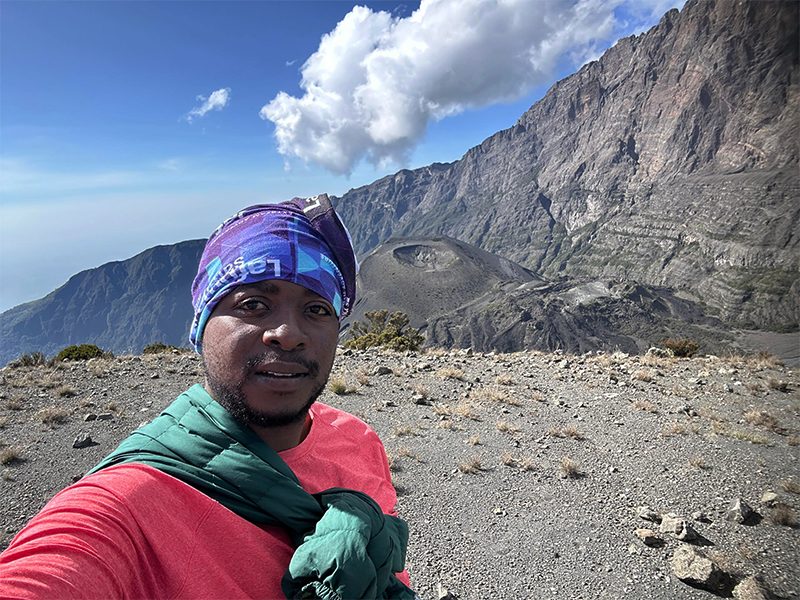 Our experienced guides also lead treks up Mount Meru — here standing near the summit with the volcano’s striking ash cone below