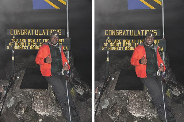 Kili Quests guide standing at the summit of Mount Meru in early morning darkness before sunrise, with limited visibility