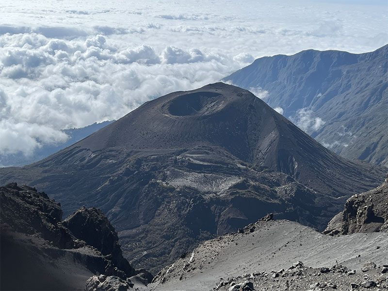 iew of Mount Meru’s steep volcanic cone surrounded by crater walls and mist, illustrating its dramatic geological formation | Kili Quests