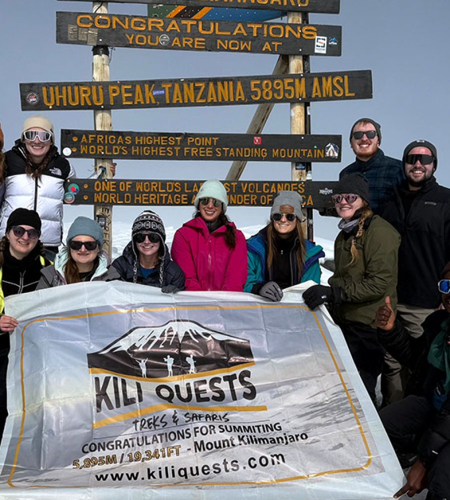Tourists celebrate their successful summit at Uhuru Peak alongside our expert KILI QUESTS guides, proudly raising the flag at Africa’s highest point.