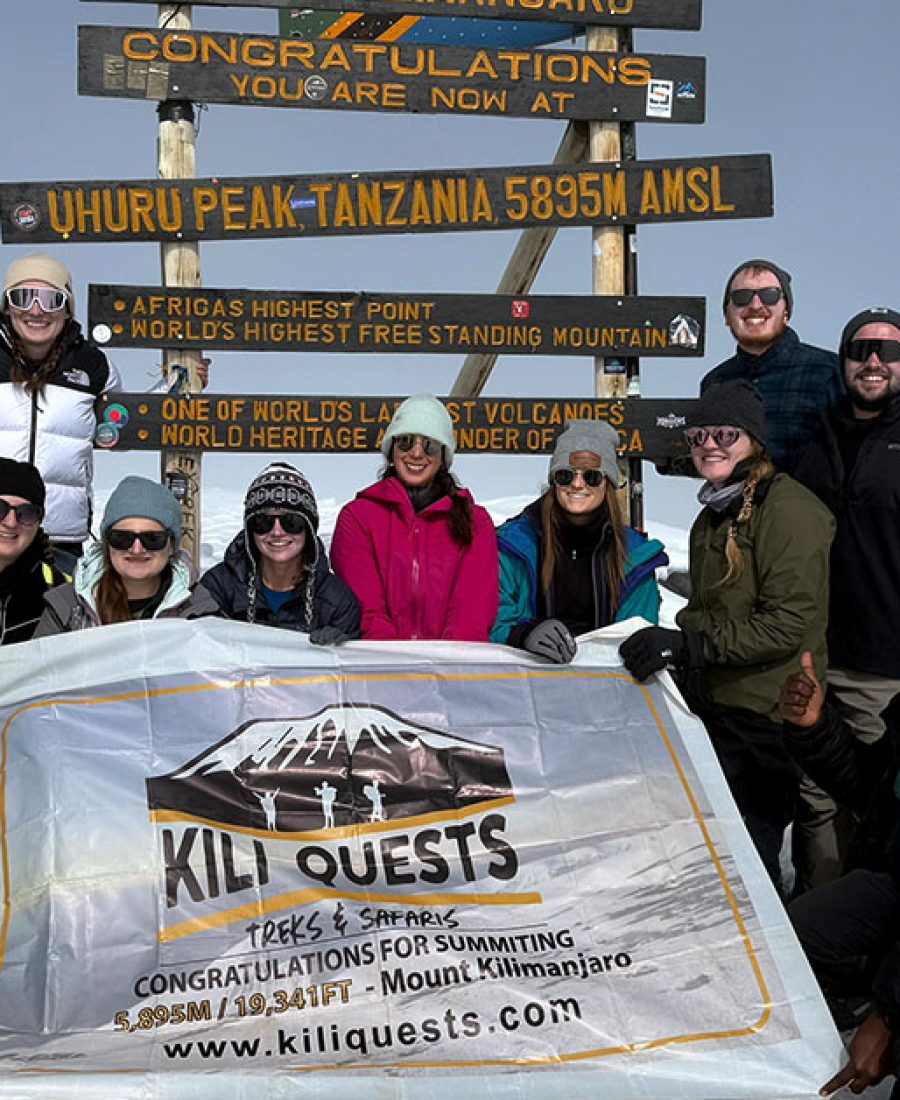 Tourists celebrate their successful summit at Uhuru Peak alongside our expert KILI QUESTS guides, proudly raising the flag at Africa’s highest point.